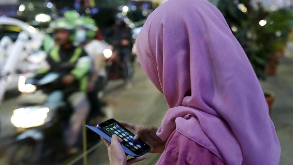 Nainen käyttää matkapuhelinta Jakartassa Indonesiassa 4.11.2015. Indonesia on väkiluvultaan maailman suurin muslimimaa.