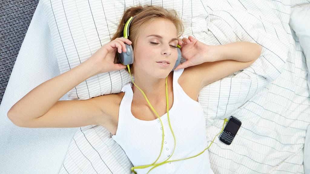 Nainen makaa, kuulokkeet