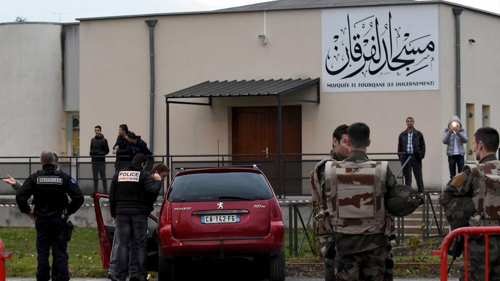 Ranskalaisia poliiseja ja sotilaita auton vieressä, jolla mies yritti ajaa sotilaiden ylitse. Taustalla näkyy moskeija, joita sotilaat olivat vartioimassa.