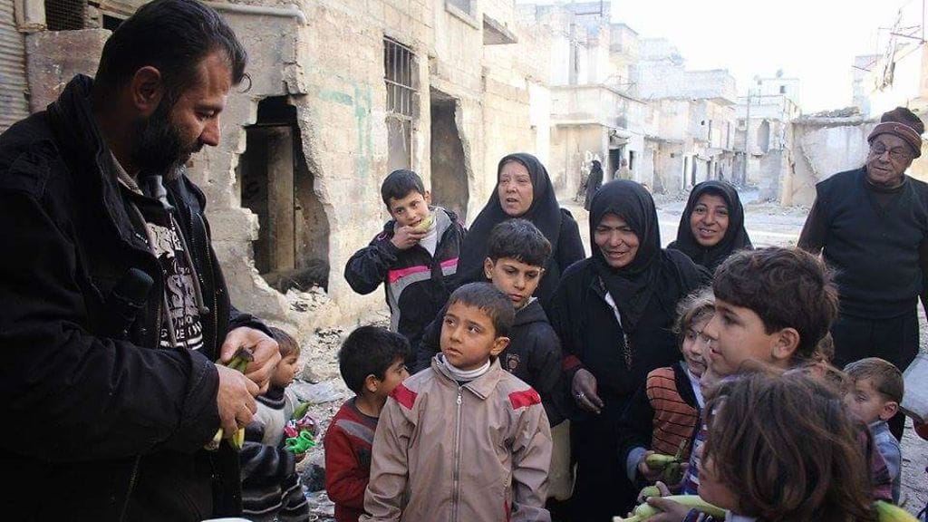 Rami Adham Syyriassa jakamassa ruokaa lapsille.