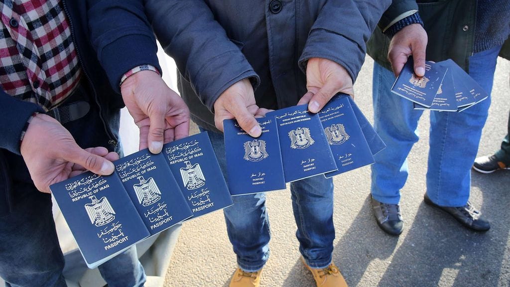Turvapaikanhakijat esittelevät Irakin ja Syyrian passeja.