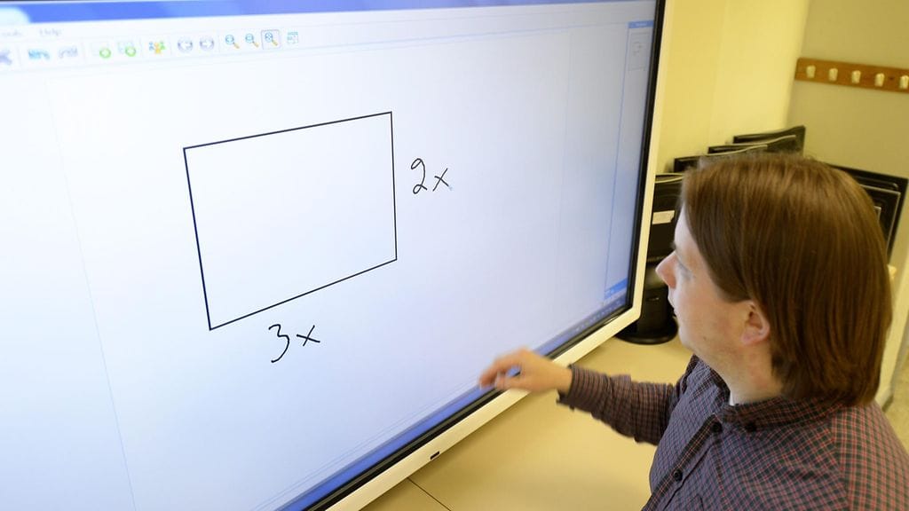 Opettaja Juhani Kivimäki esittelee opetuksessa käytettävää kosketusnäyttötaulua Etu-Töölön lukiossa Helsingissä.