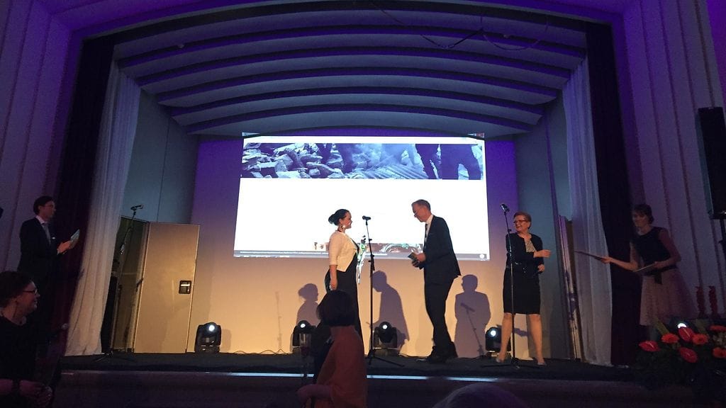 Mona Haapsaari vastaanottaa kunniamaininnan jutustaan.