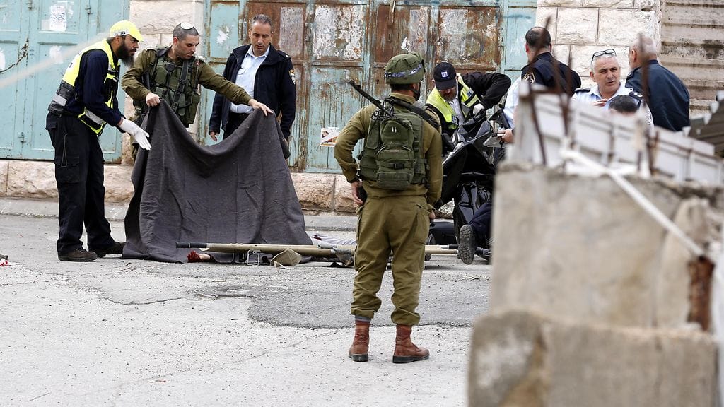 Israelilaissotilaat peittävät huovalla palestiinalaisen ruumiin ammuskelun jälkeen Tal Rumaidassa Hebronisssa. Kaksi palestiinalaista ammuttiin puukotuksen jälkeen paikalla.