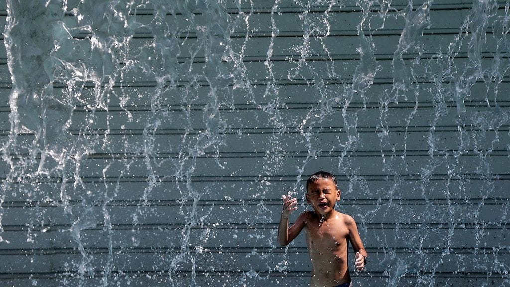 Lapsi päätti ottaa kylvyn suihkulähteessä helteisessä Kuala Lumpurissa 29. maaliskuuta 2016.