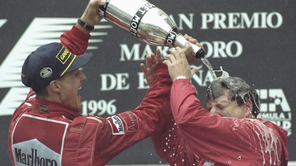 Michael Schumacher kastelee tallipäällikkö Jean Todtin Barcelonan palkintopallilla 1996.