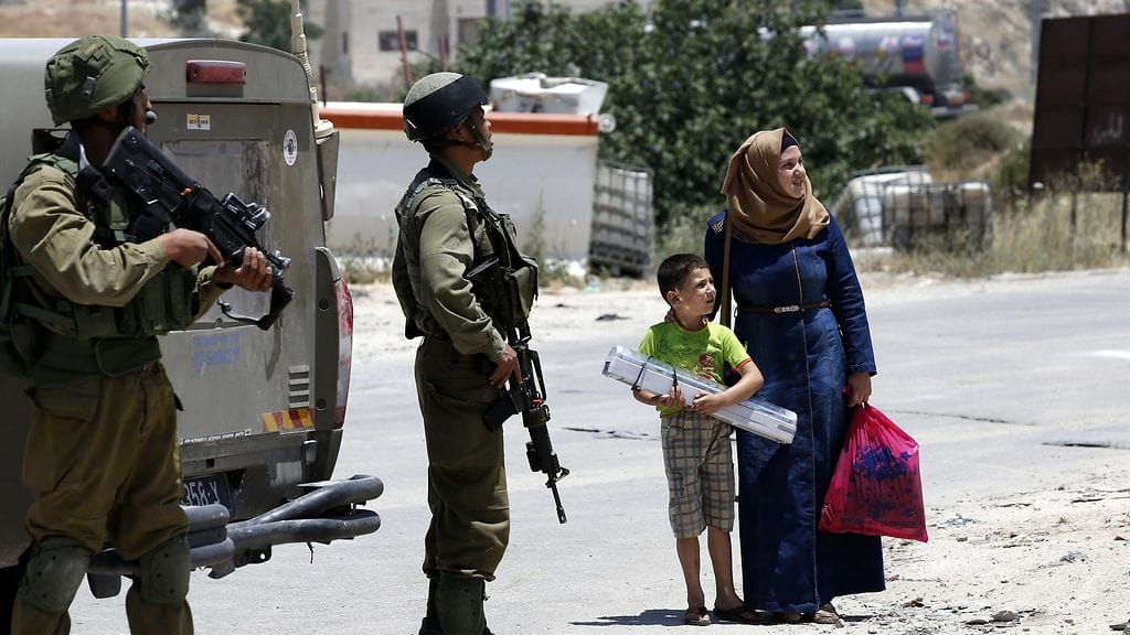Palestiinalaisperhe seisoo Israelin tarkastuspisteellä. Israelin armeija määräsi Yattan kylän Länsirannalla suljetuksi sotilasalueeksi torstaina.