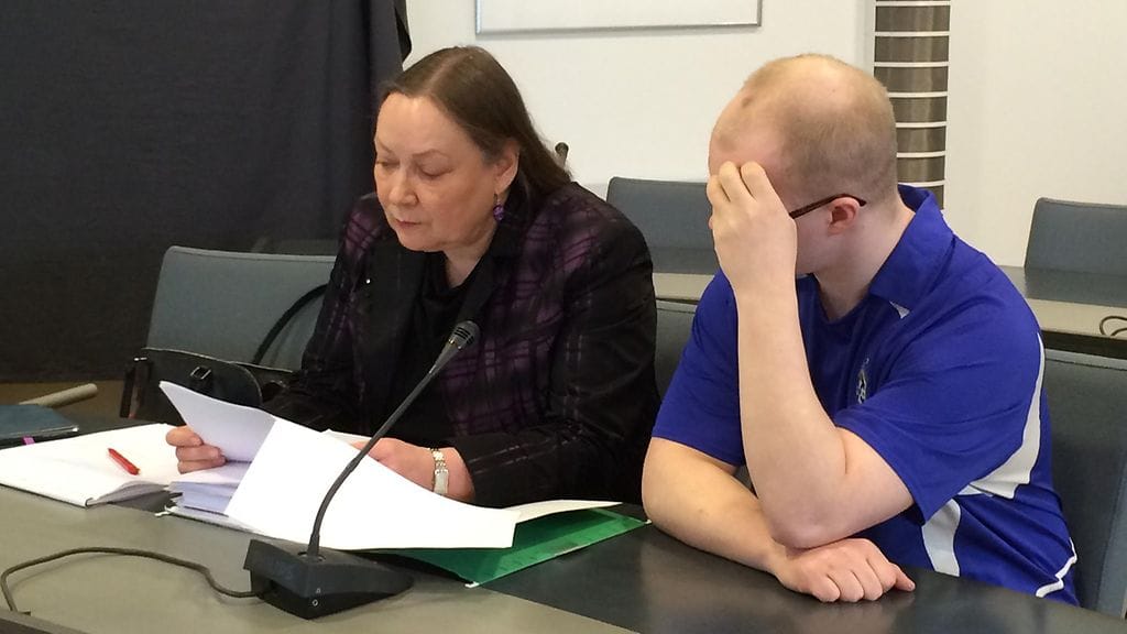 Raiskauksista syytetty Miko Ville Kristian Huittinen peitti kuvauksen aikana kasvonsa kädellään. Vierellä avustaja Anne Harsio.