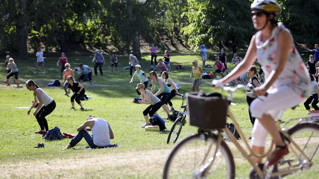 Puistojumppaa ja pyöräilijä Helsingissä Hesperian puistossa Töölönlahden rannassa tiistaina 1. kesäkuuta.