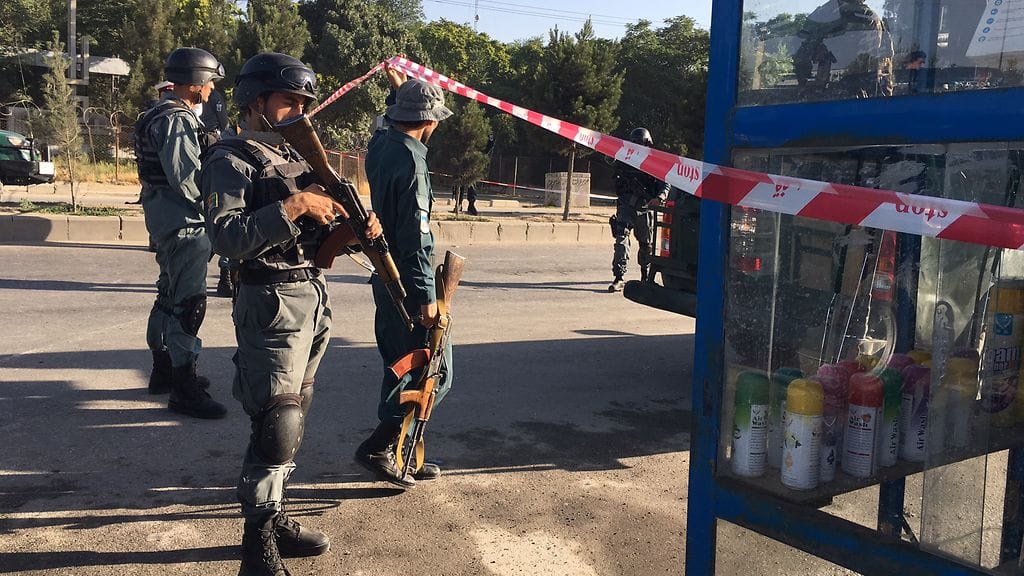 Aseistautuneet Afganistanin viranomaiset tutkivat paikkaa, jossa itsemurhapommittaja iski minibussiin.