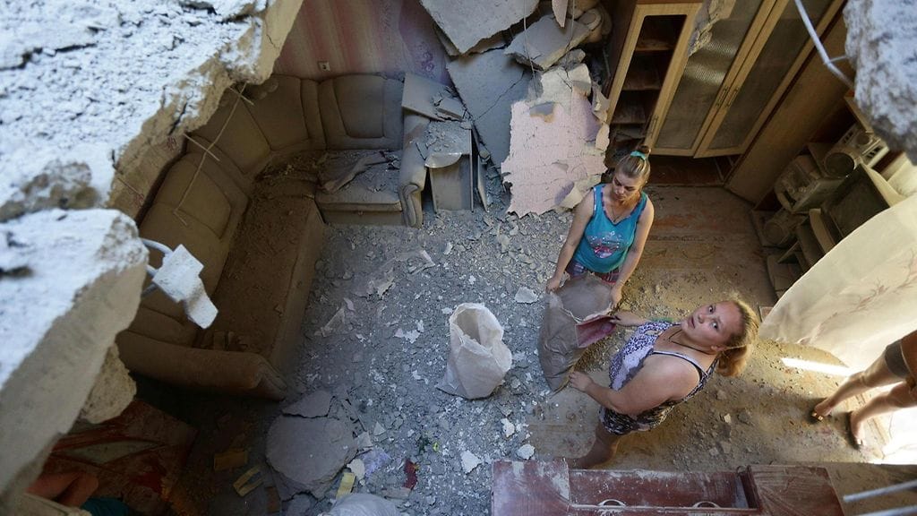 Paikallisia asukkaita talon raunioissa Donetskin kaupungissa Itä-Ukrainassa 24. kesäkuuta 2016.