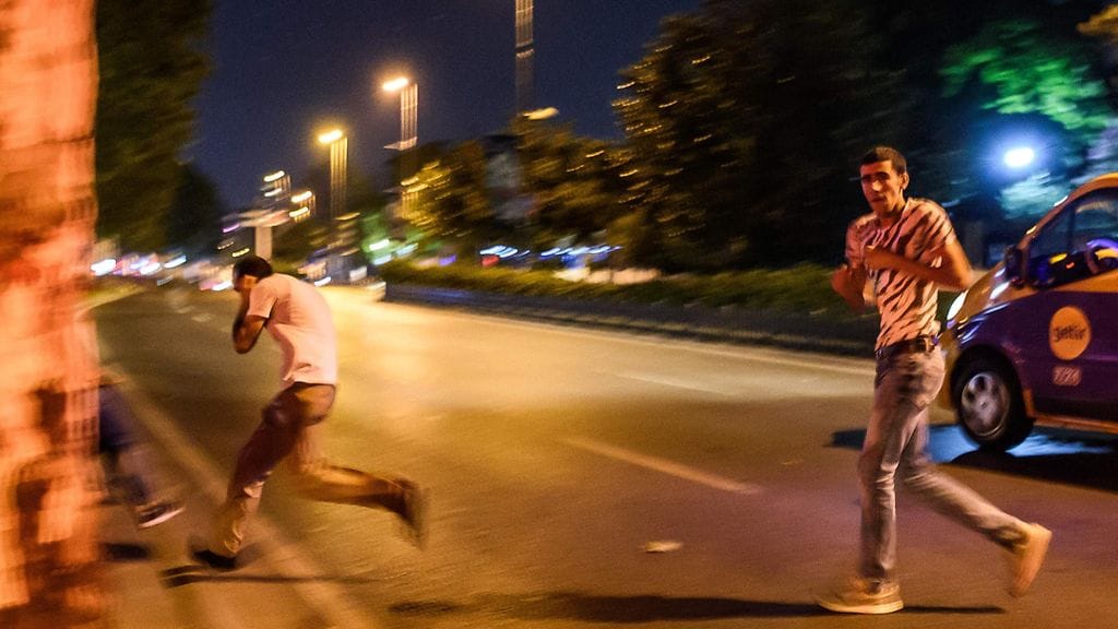 Ihmiset suojautuivat turkkilaissotilaiden ja poliisin väliseltä tulitukselta yöllä lähellä Taksimin aukiota Istanbulissa.