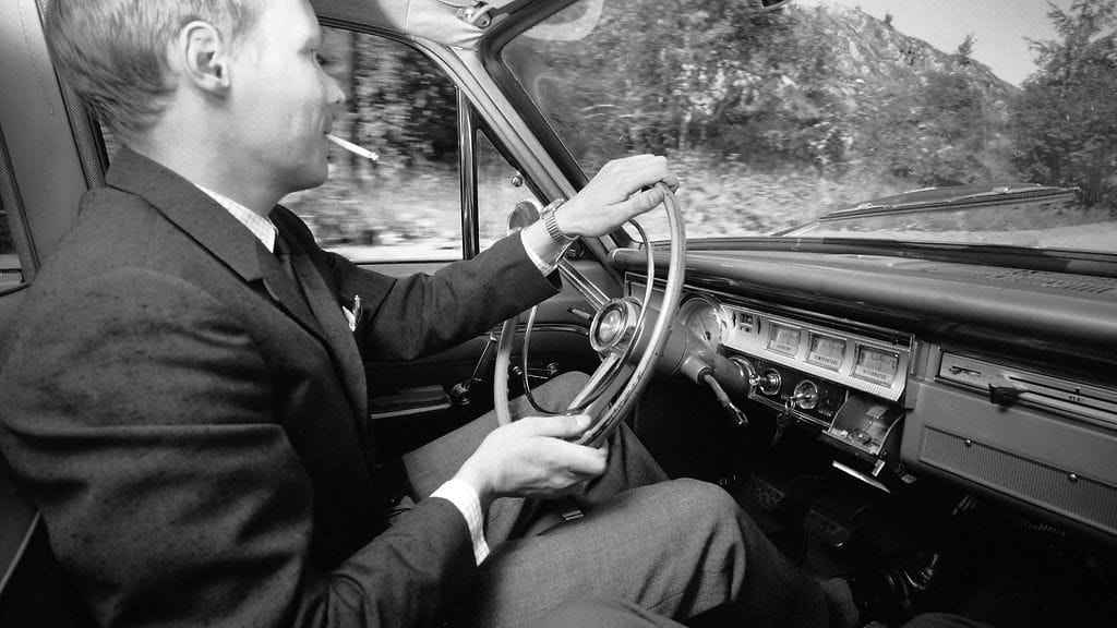 Mies tupakoi ajaessaan vuodelta 1966 peräisin olevassa kuvassa.