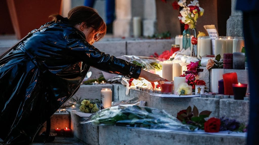 Nainen toi kynttilän Ranskan kirkkoiskun uhrien muistopaikalle. Panttivankitilanteessa kuoli kirkon pappi.