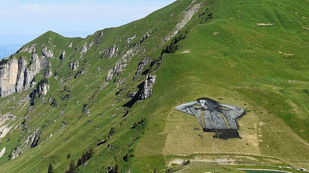 Kuvassa on sveitsiläinen paimen maalattu biologisesti hajoavilla maaleilla. Maalaus on tehty sveitsiläiselle pellolle ja sen on tehnyt ranskalainen taiteilija Saype. Maalaus on 10 000 neliömetrin kokoinen.