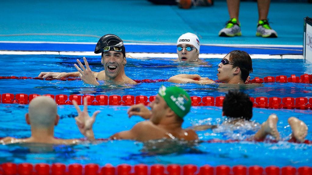 Michael Phelps viittoilee - hopea meni jakoon kolmelle.