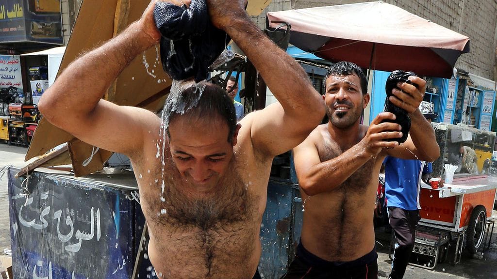 Miehet viilensivät itseään kastelemalla vaatteitaan Baghdadissa Irakissa 21. heinäkuuta 2016. Mediatietojen mukaan lämpötilat nousivat silloin alueella yli 50 celciusasteen.