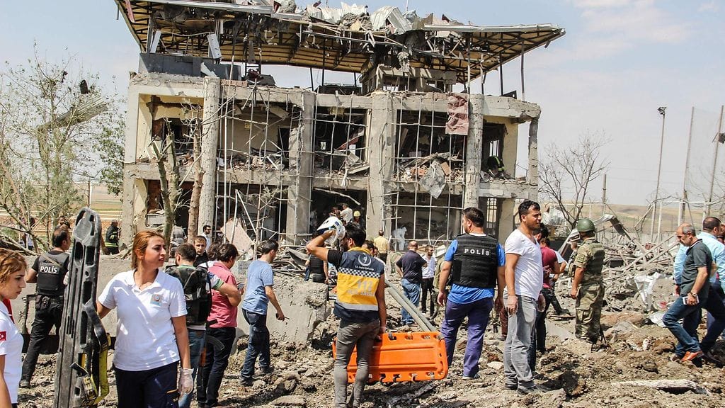 Turkin poliisi ja pelastusviranomaisia paikalla, jossa autopommi räjähti Diyarbakirin kaupungin lähellä 15. elokuuta.