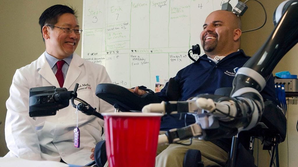 Erik Sorto (oik.) ajattelee kupin nostamista ja robottikäsi alkaa toimia. Neurokirurgi Charles Y. Liu johti lääkäriryhmää, joka sai sirun avulla yhteyden Sorton aivoista robottikäteen.