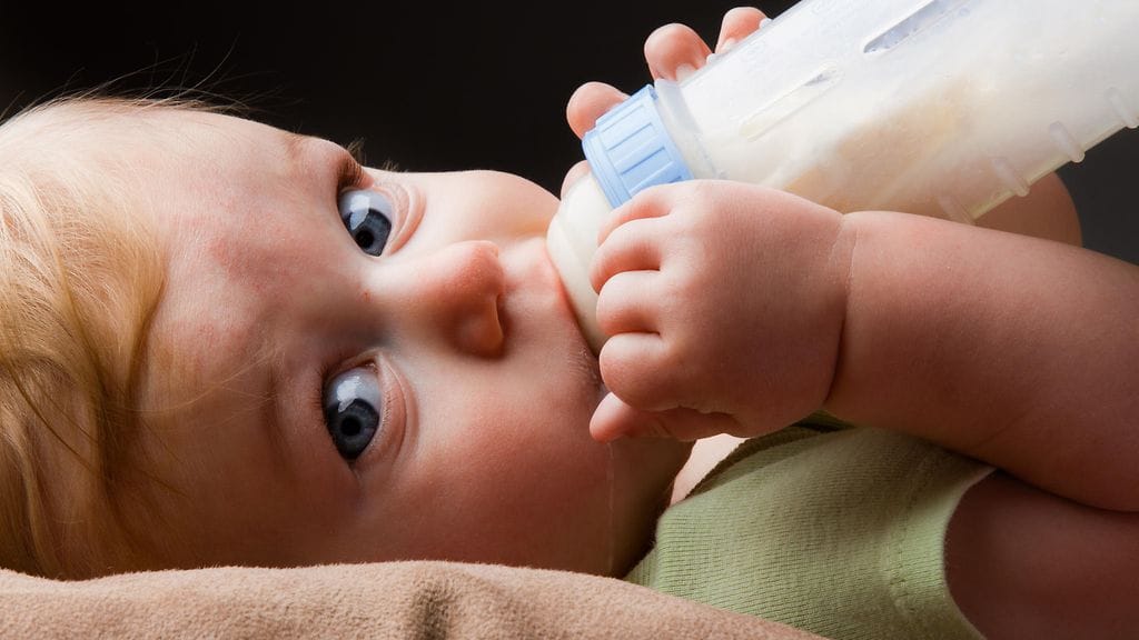 Vauva juo tuttipullosta äidinmaidonkorviketta. Kuvituskuva.