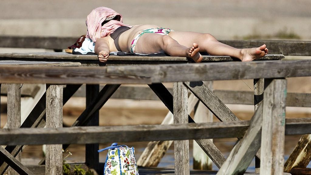 Osittain suojautunut auringonottaja Mattolaiturilla Helsingissä 27. heinäkuuta 2016.