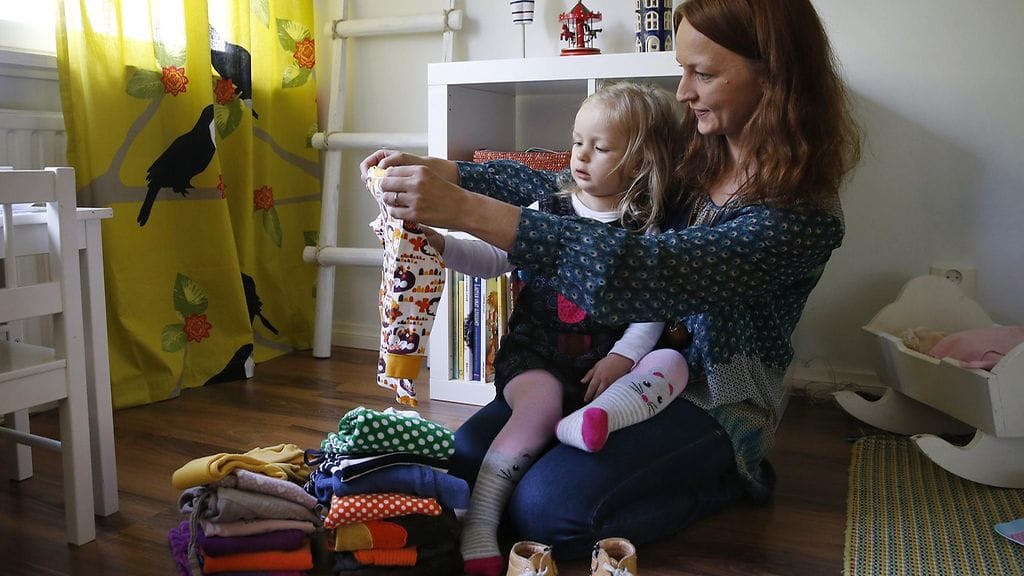 Heidi Jacobson ja hänen 2-vuotias Meri-tytär katselevat lastenvaatekirpputorilta löytämiään lastenvaatteita Oulussa.