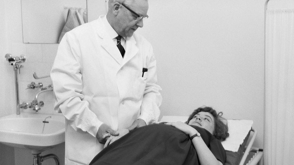 Synnytyssairaala Kätilöopiston ensimmäinen vauva syntyi 1960. Synnytyslääkäri tutkii raskaana olevaa rouvaa.