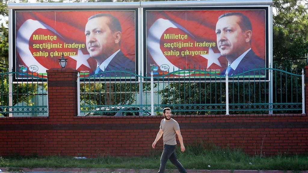 Kuvituskuvassa turkkilaismies kävelee presidentti Recep Tayyip Erdoganin julisteen edestä.