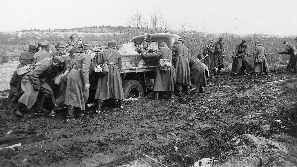 Sotilaita yrittämässä irrottaa mutaan juuttunutta autoa jatkosodan aikana. Toivo Salmen kotiarkisto.