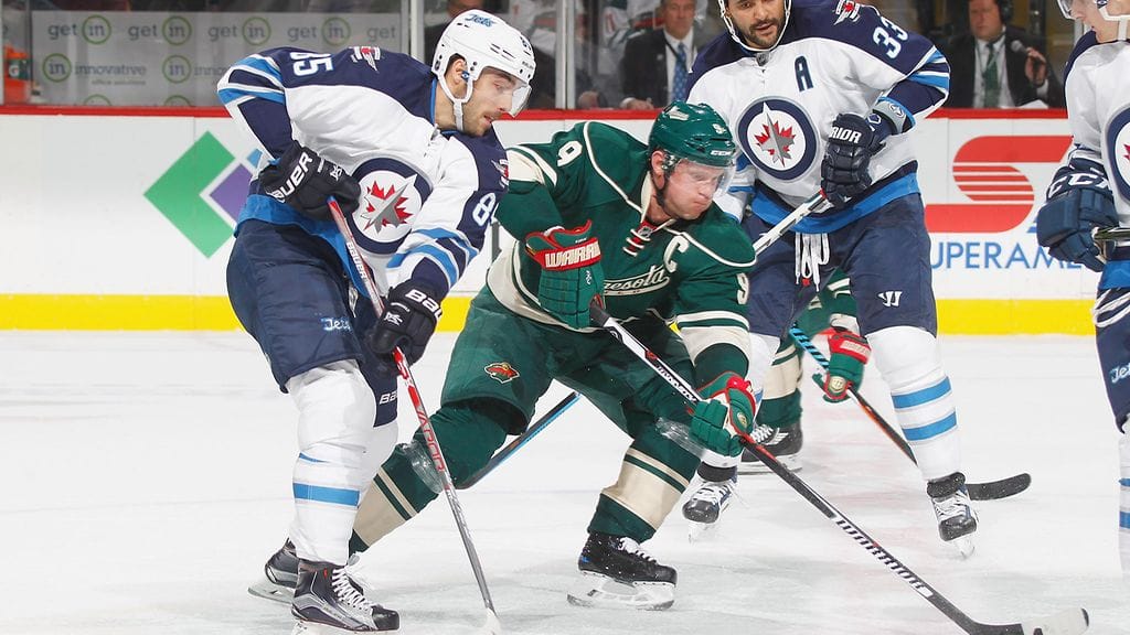 Mikko Koivu Jets-pelaajien puristuksessa.