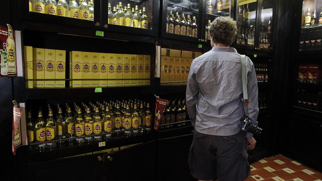Turisti tutkailee Havana Club -rommia kaupassa Havannassa.