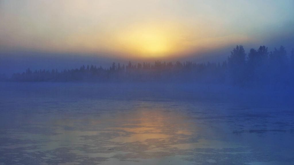 Usvainen aurinko laskee Oulujoella Vaalassa. Lukijan kuva.