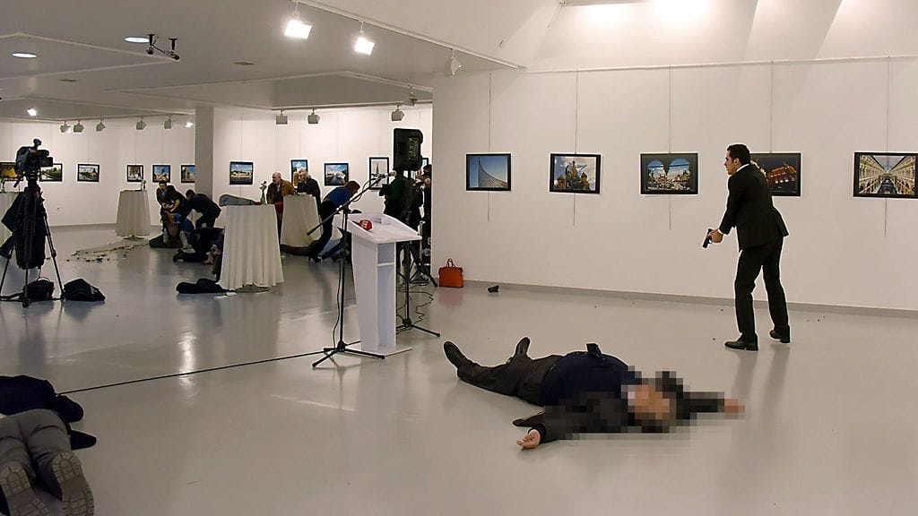 This picture taken on December 19, 2016 shows Andrey Karlov (2ndR), the Russian ambassador to Ankara, lying on the floor after being shot by a gunman (R) during an attack during a public event in Ankara. A gunman crying "Aleppo" and "revenge" shot Karlov while he was visiting an art exhibition in Ankara on December 19, witnesses and media reports said.
