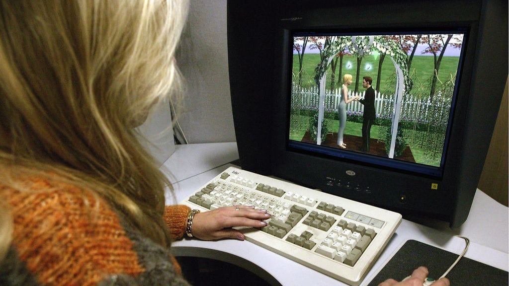 Nainen pelaa The Sims 2 -peliä tietokoneellaan.