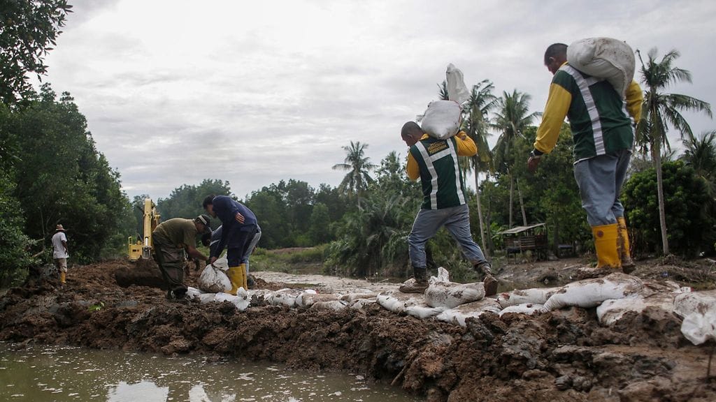 Arkistokuva. Miehet korjasivat rikkoutunutta patoa Malesian Kaparissa lokakuussa 2016.