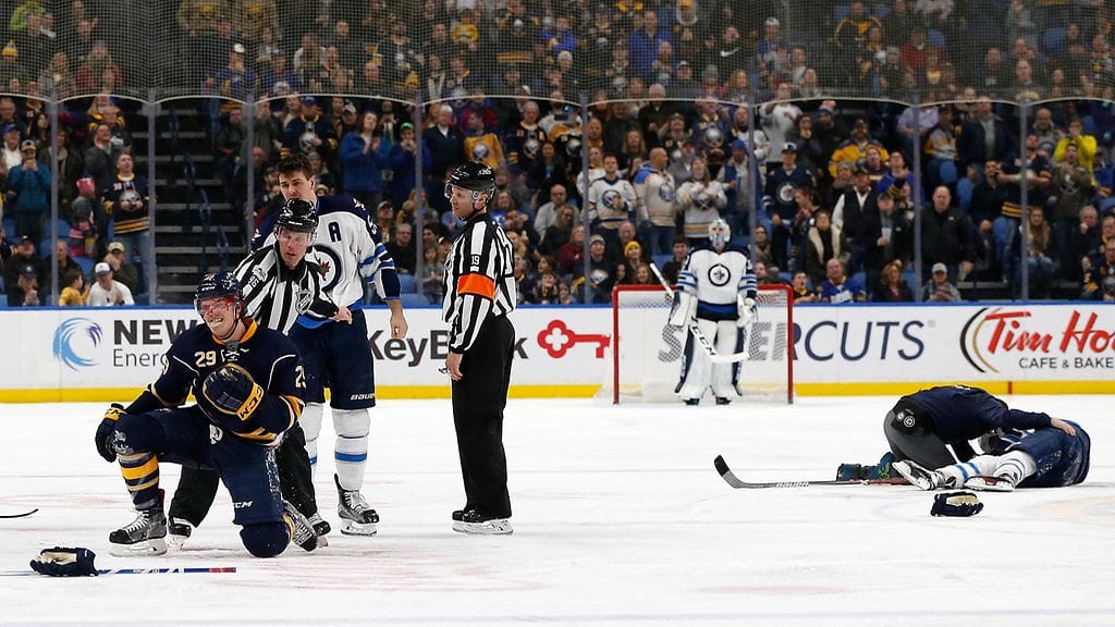 Jake McCabe (vas.) joutui Jets-pelaajien hampaisiin taklattuaan Patrik Lainetta (oik.).