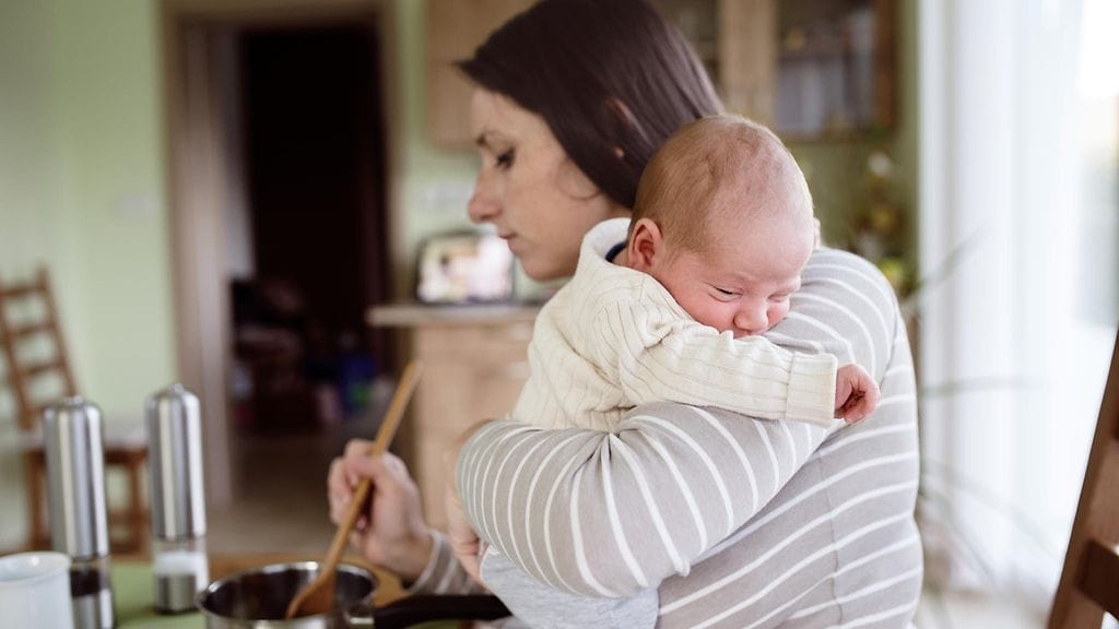 Vauva sylissä voi olla vaikea laittaa ruokaa turvallisesti. Kuvituskuva.