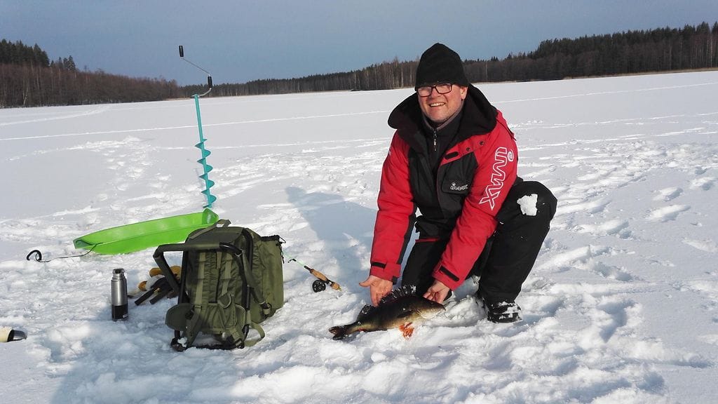 Ari Oksiala jättiahvenen kanssa pilkkipaikalla. Kuva Esa Hämäläinen.