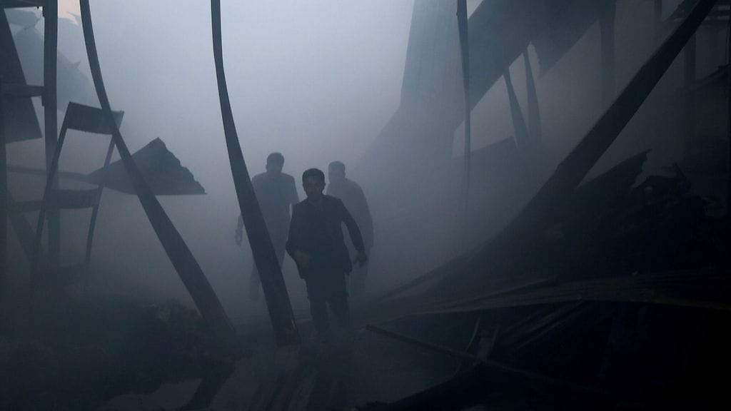 Henkilöt kulkevat tuhoutuneen rakennuksen raunioissa Syyriassa. Arkistokuva.