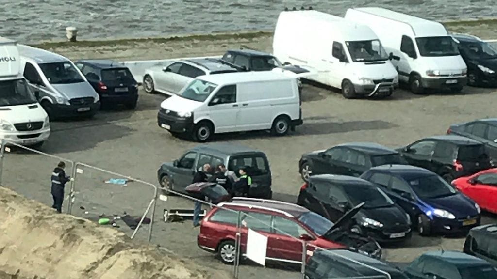 Poliisi tutkii väkijoukkoon ajanutta autoa Antwerpenissä parkkipaikalla. Mies on poliisin hallussa.