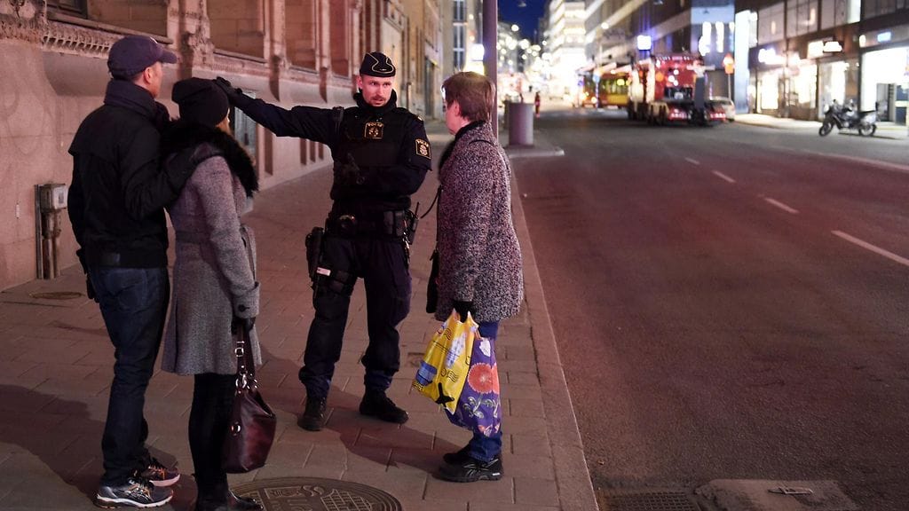 Poliisi antoi ohjeita kadulla kulkeville ihmisille Tukholman keskustassa illalla.