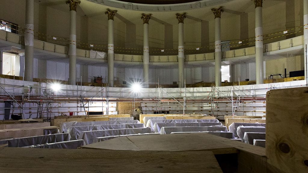 Eduskuntatalon peruskorjaus. Rakennustelineet on pääosin saatu purettua täysistuntosalista. Kunnostetut kansanedustajien pöydät ovat vielä osittain vanereiden alla suojassa.