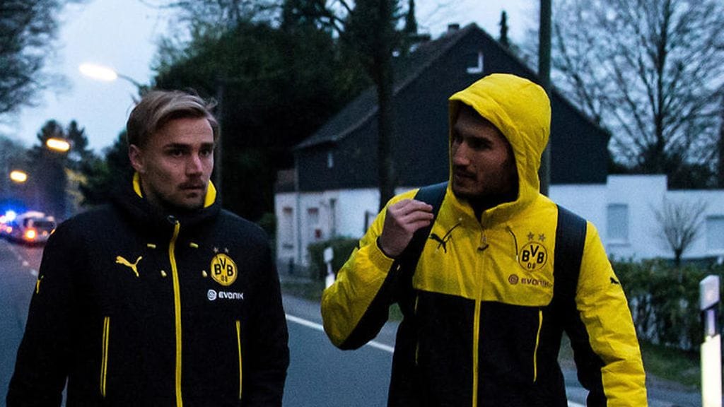 Marcel Schmelzer (vas.) ja Nuri Sahin poistumassa bussi-iskun paikalta tiistaina.