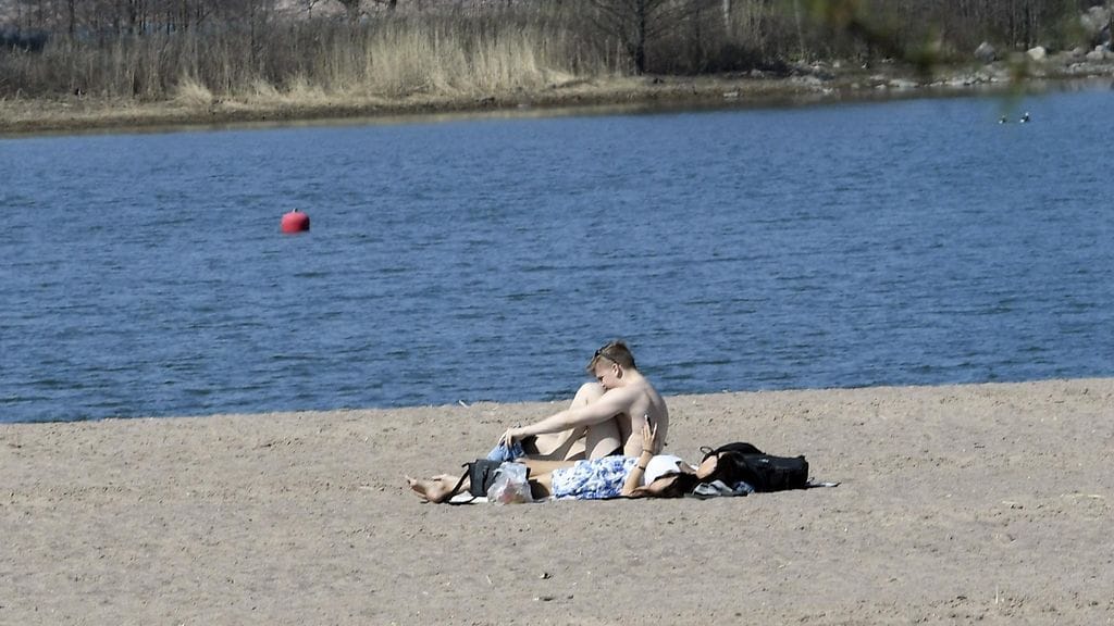 Ihmiset nauttivat auringosta Hietaniemen hiekkarannalla Helsingissä.