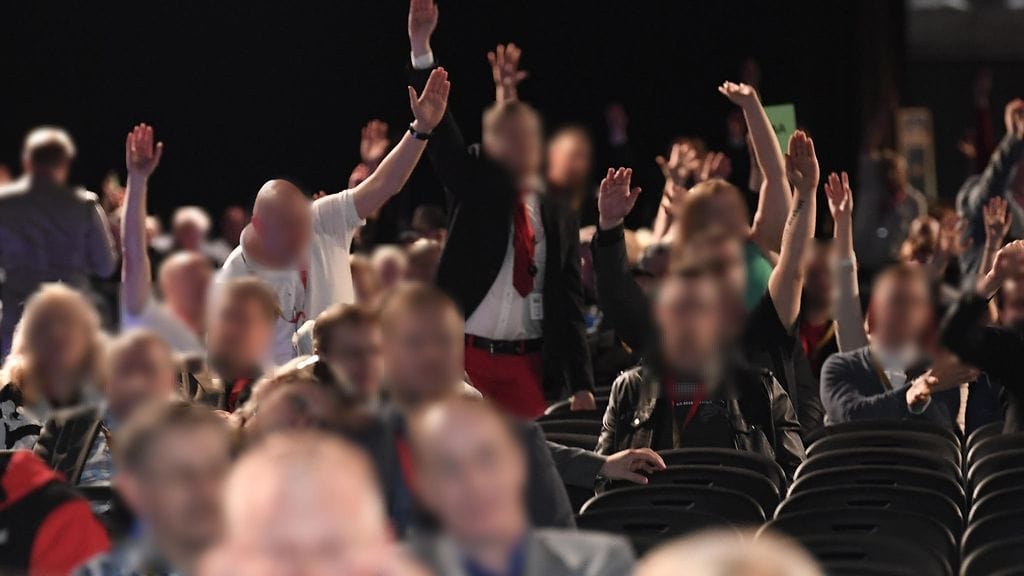 Tästä kuvasta nousi kohu, kun perussuomalaisista irtautuneen kansanedustaja Tiina Elovaara kertoi Ylen A-Studiossa nähneensä käsitervehdyksiä puoluekokouksessa. Kuvassa on kuitenkin kyse käsiäänestyksestä, jossa puolueväki yrittää sopia äänestystavasta. Osa kuvan henkilöistä teki kunnianloukkauksesta rikosilmoituksen, mutta Helsingin poliisi ei aio aloittaa tapauksesta esitutkintaa. Alkuperäistä Lehtikuvan kuvaa on muokattu, jotta kuvan henkilöt eivät olisi tunnistettavissa.