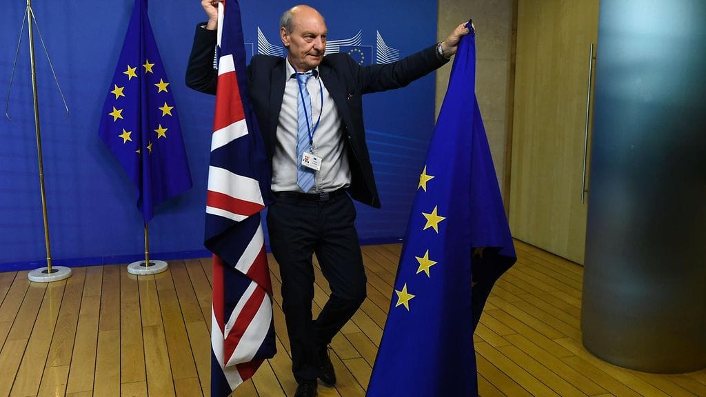 EU-virkailija kantaa Britannian ja EU:n lippuja Brysselissä brexit-neuvottelujen alkamispäivänä 19. kesäkuuta 2017.
