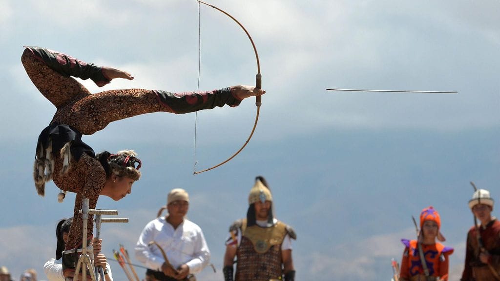 Kirgisialaisnainen näyttää esimerkkiä, että onnistuu se jousiammunta jaloillakin. Kuva otetti maan etnofestivaaleilla Tonin kylässä 350 kilometriä pääkaupunki Bishkekistä 15. heinäkuuta 2017.