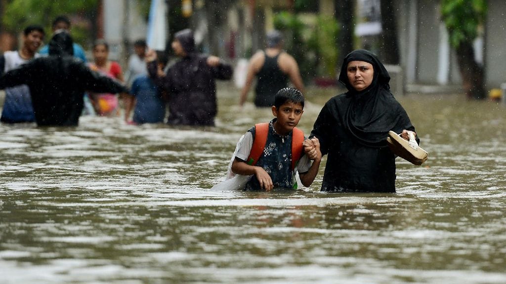 Intialainen äiti ja poika kahlasivat tulvavedessä Mumbaissa tiistaina.