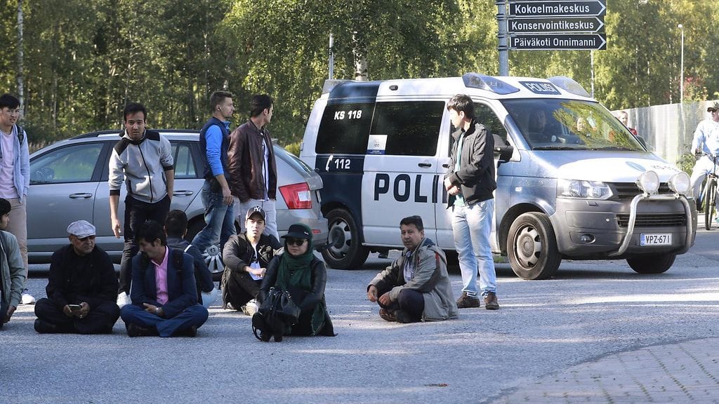 Mielenosoittajat istuivat vastaanottokeskuksen edustalla kuusituntiseksi venyneen karkotustehtävän aikana.