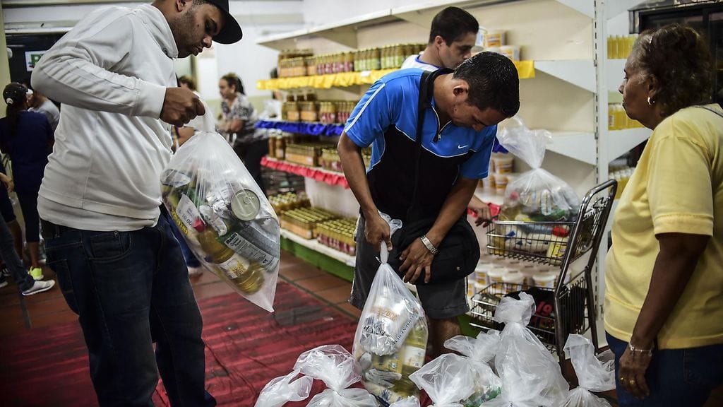 Ihmiset hakemassa ruokaa Venezuelassa ruoanjakelukeskuksesta elokuussa.